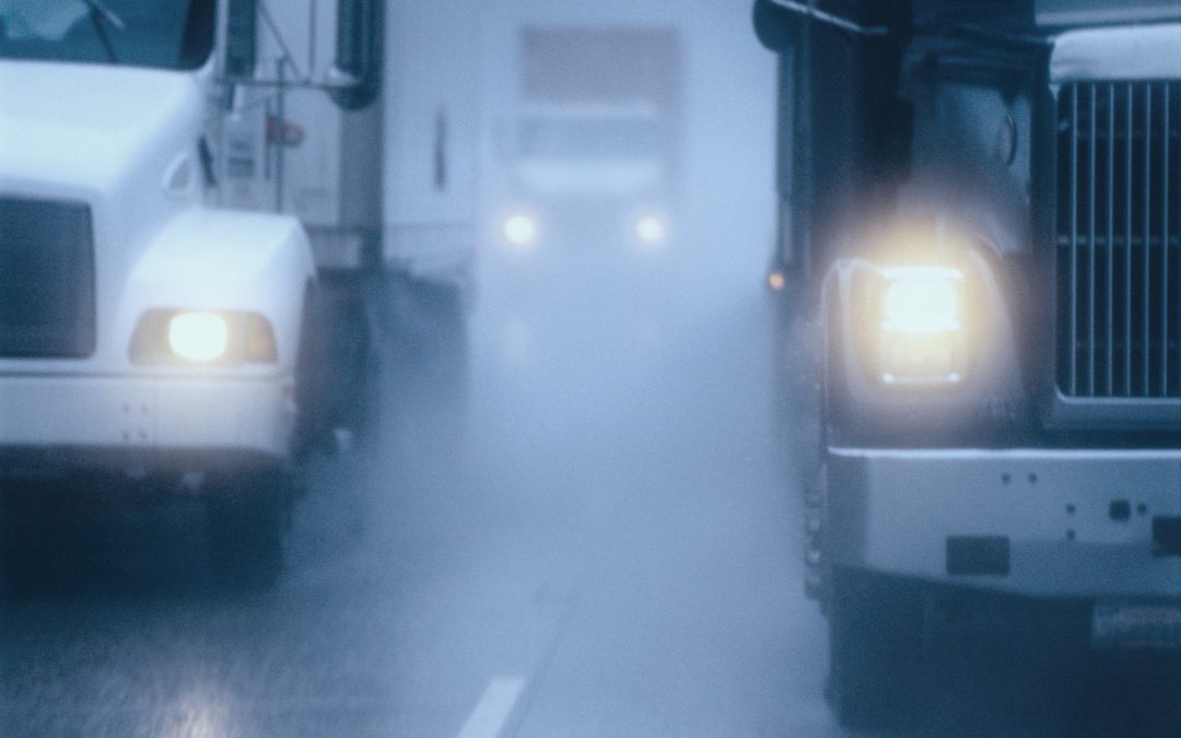 Partial view of large semis driving closely in bad weather