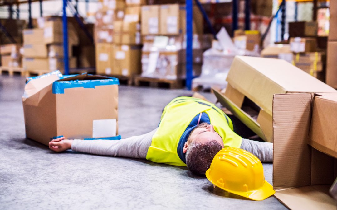 An accident in a warehouse. Man lying on the floor among boxes, unconscious.