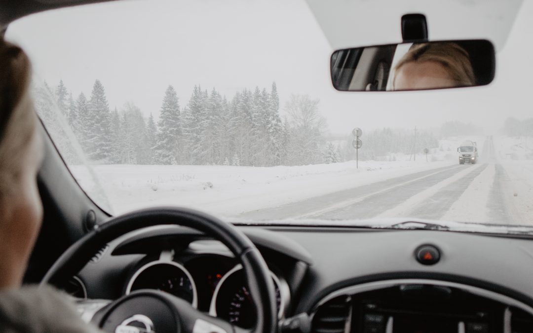 View from the backseat of a woman driving towards a truck on a snowy road.