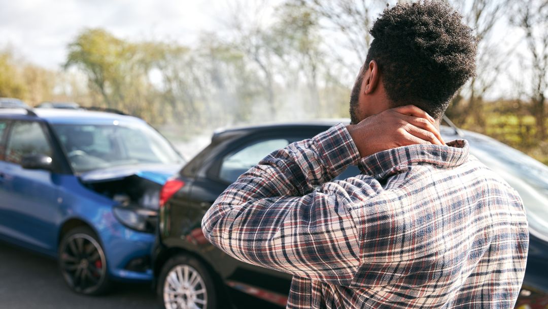 man holding his neck in pain from car crash