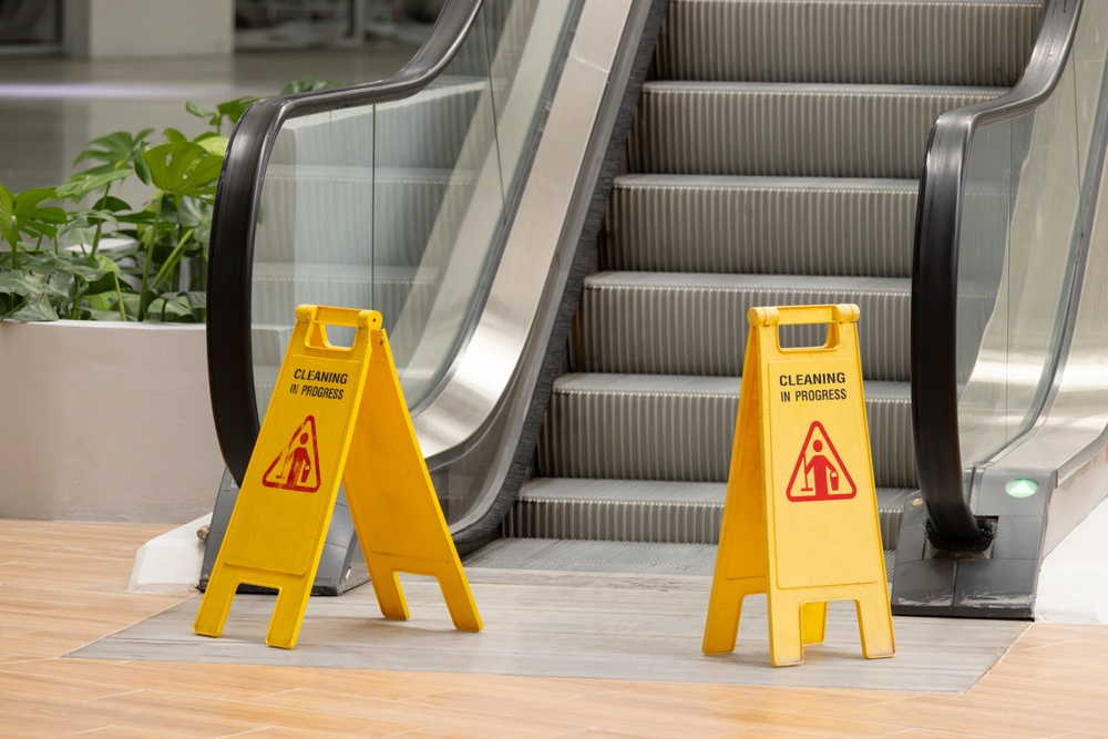Wet floor signs blocking the foot of an escalator