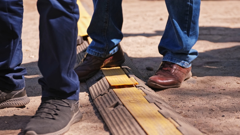 Close-up of feet stepping over covered electrical cables on construction site
