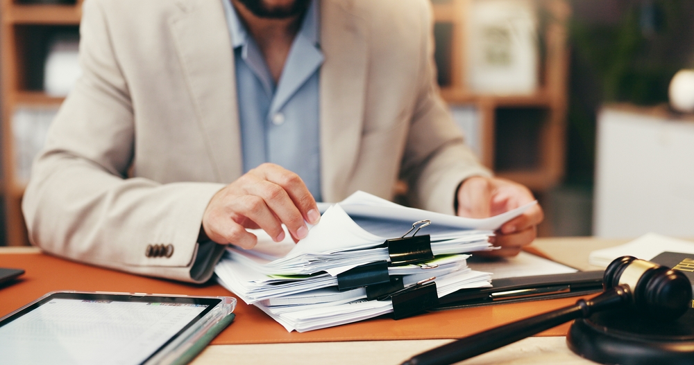 Close-up image of lawyer's hands looking through documentation on desk