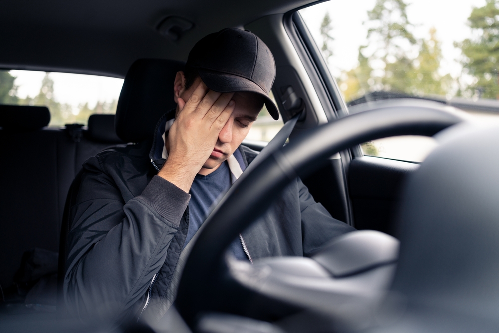 Drowsy driver rubbing eyes behind the wheel