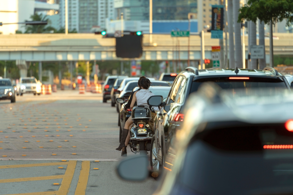 Motorcycle stopped in traffic at intersection with standard car traffic