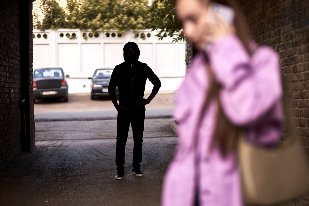 Person following unaware woman from unmonitored alley