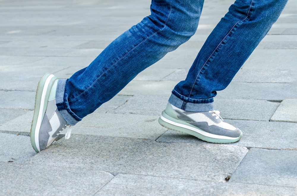 Close-up of a woman's feet as she catches her toe on a sunken paver