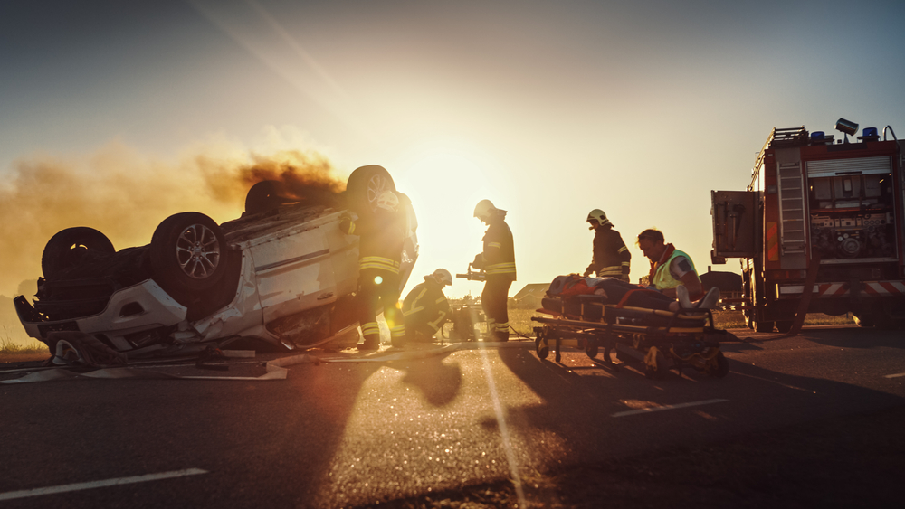 On the Car Crash Traffic Accident Paramedics and Firefighters Rescue Injured Trapped Victims. Medics give First Aid to Female on Stretchers. Firemen Use Hydraulic Cutters Spreader to Open Vehicle